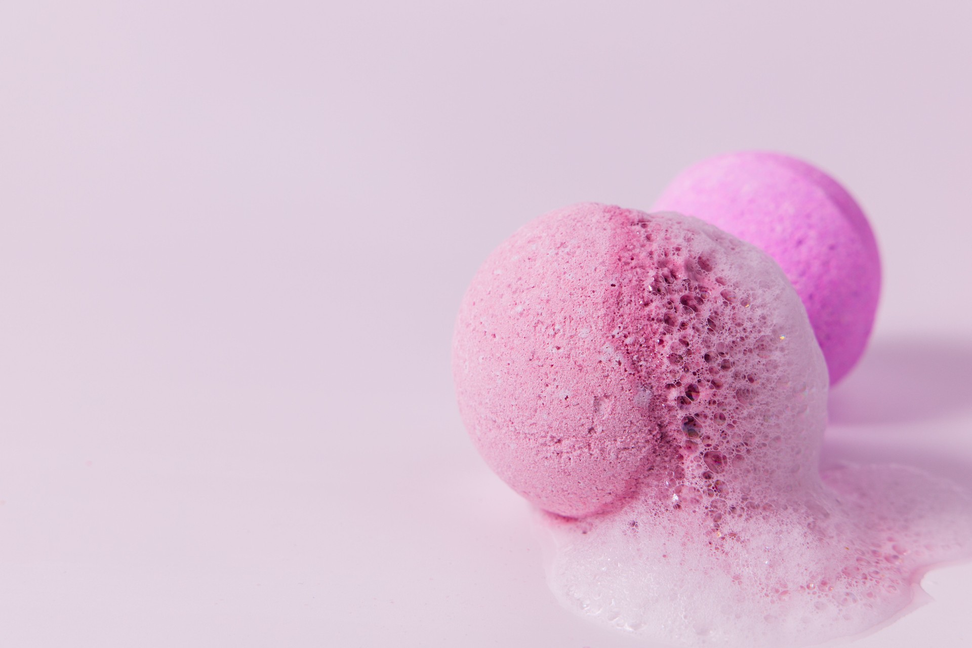 Colorful bath bombs fizzing on a light pink surface in a relaxing atmosphere